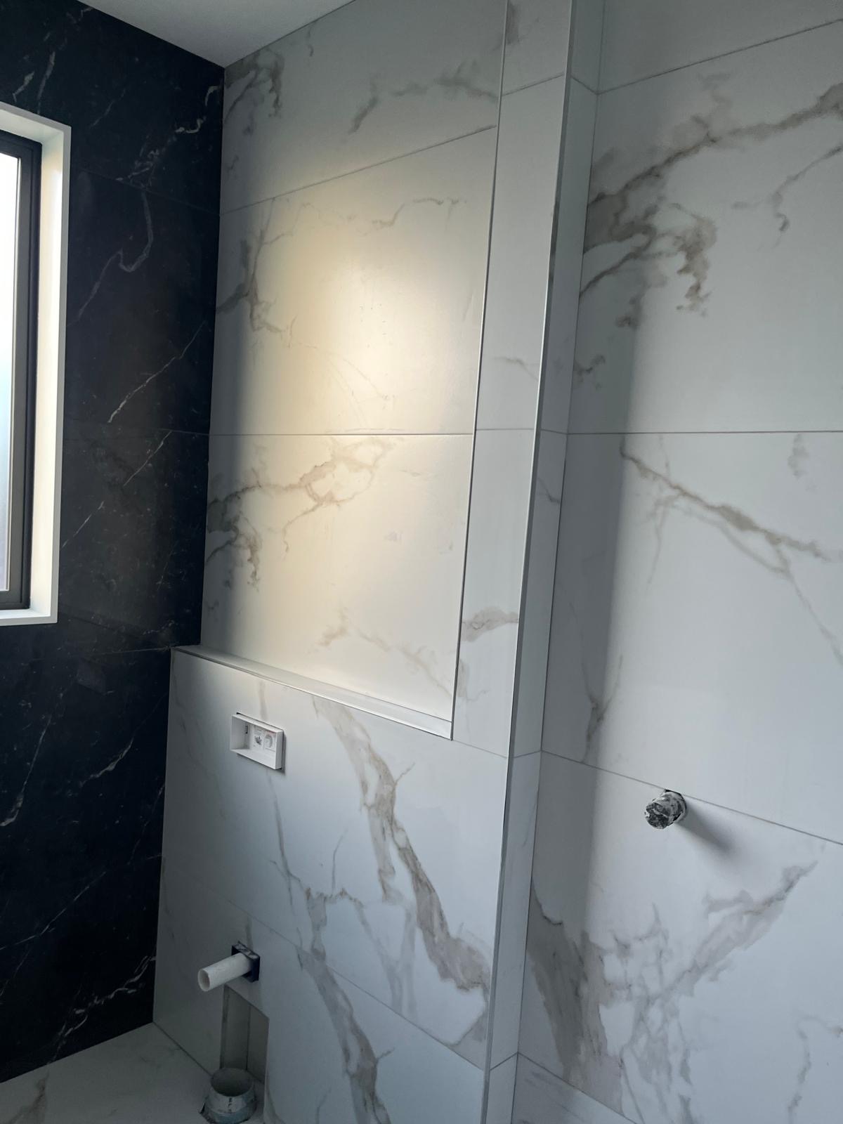 Finished bathroom tiling with niche shelf and towel rail